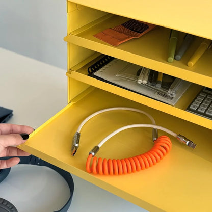 Detail shot of a hand pulling out a tray from the Sunny Yellow metal organizer to reveal a cable - RoomDen.
