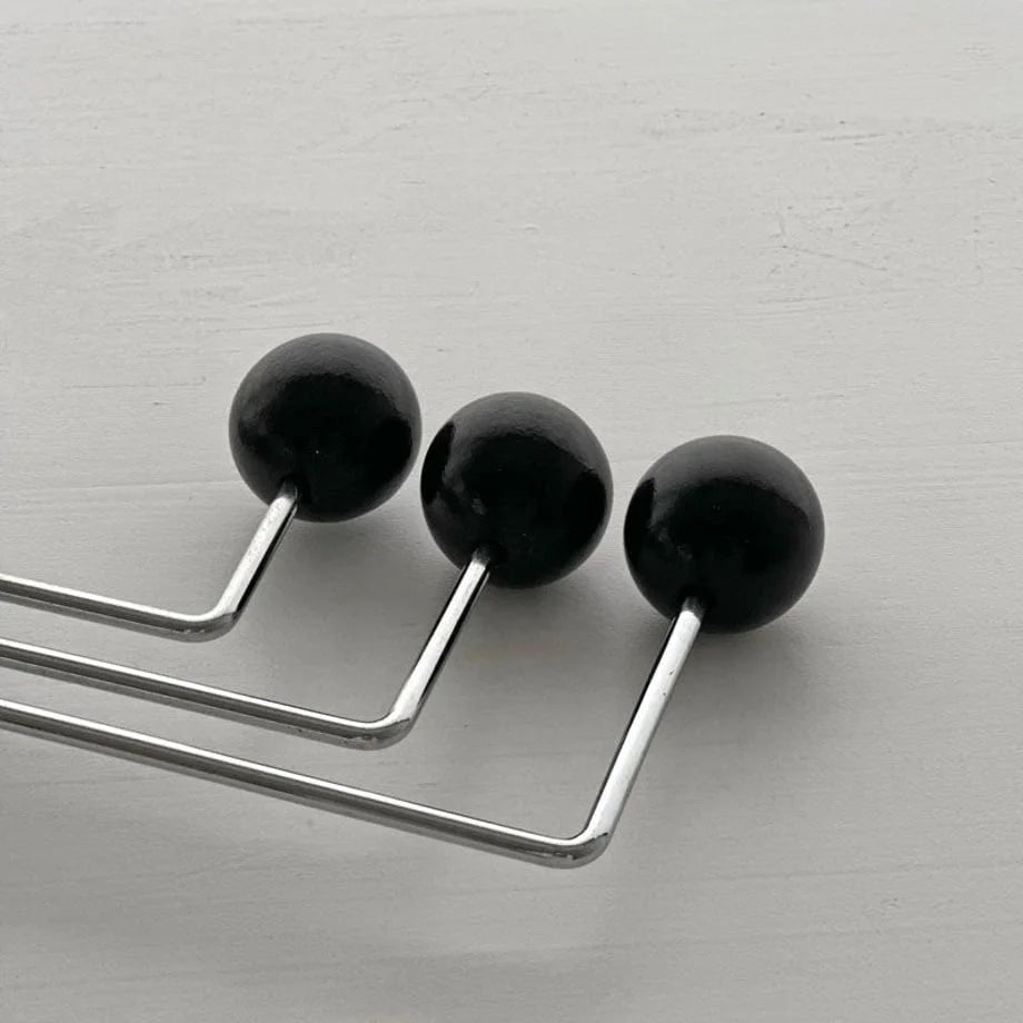 Macro detail shot of the three smooth black spheres on the swivel metal wall hook - RoomDen.