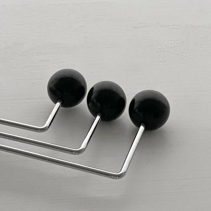 Macro detail shot of the three smooth black spheres on the swivel metal wall hook - RoomDen.