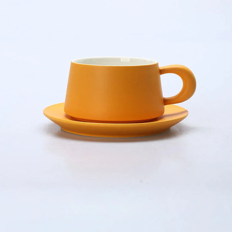 Side view of the Marigold Orange matte ceramic coffee cup and saucer set against a white background. - RoomDen