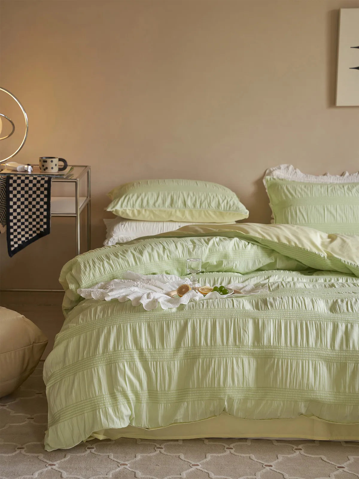 Pistachio Green pintuck bedding set in a cozy, beige-walled bedroom with a side table. - RoomDen