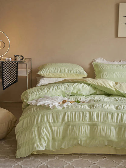 Pistachio Green pintuck bedding set in a cozy, beige-walled bedroom with a side table. - RoomDen