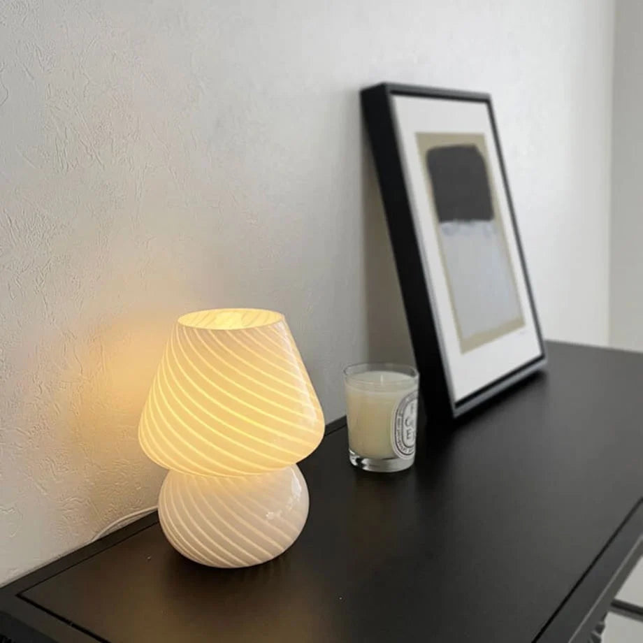 Close-up of the Swirled Glass Mushroom Lamp's texture with warm light on, next to a picture frame.