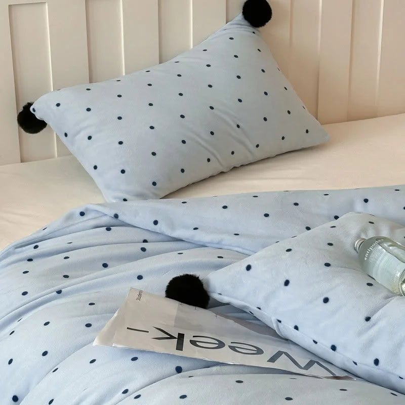 Close-up shot of the plush texture on the Baby Blue Polka Dot Velvet pillowcase with a black pom pom detail. - RoomDen