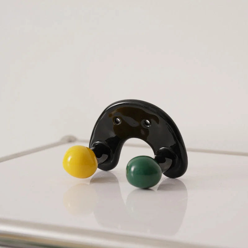 U-shaped black ceramic wall hook with one yellow and one green ball.
