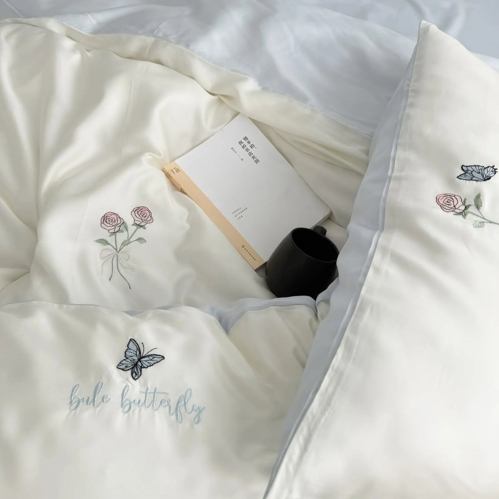 Lifestyle shot showing the Cream White version of the embroidered Tencel bedding set, with the duvet folded back. - RoomDen