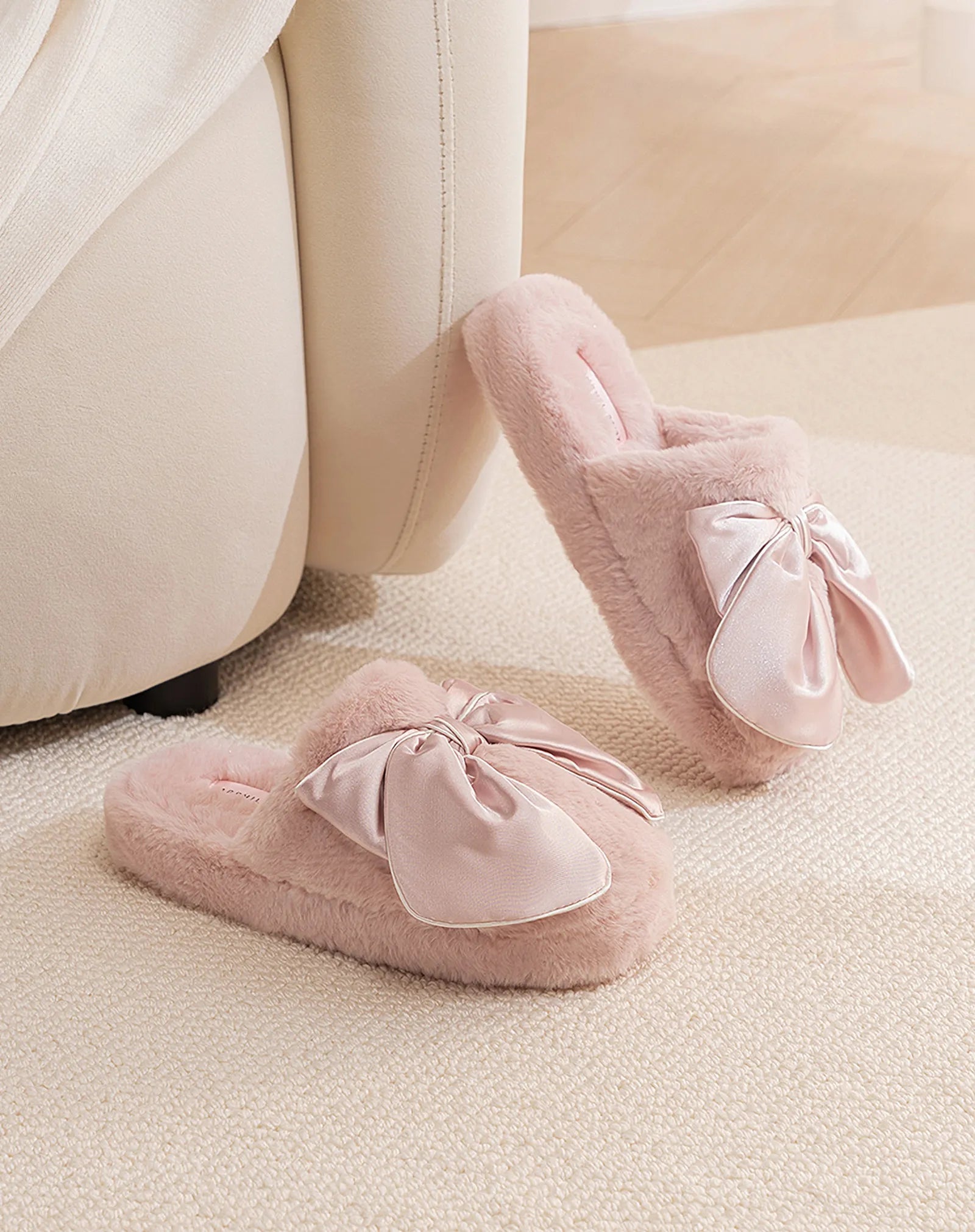 Pink Satin Bow Faux Fur House Slippers leaning against sofa