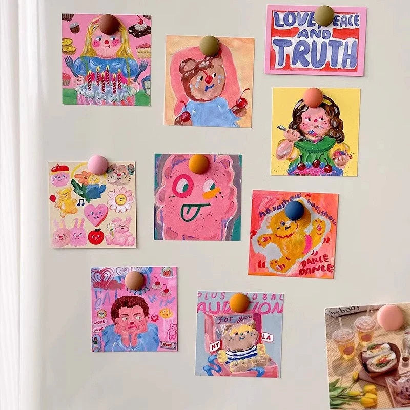 The doodle art prints from the collage kit displayed on a white refrigerator with colorful round magnets - RoomDen.