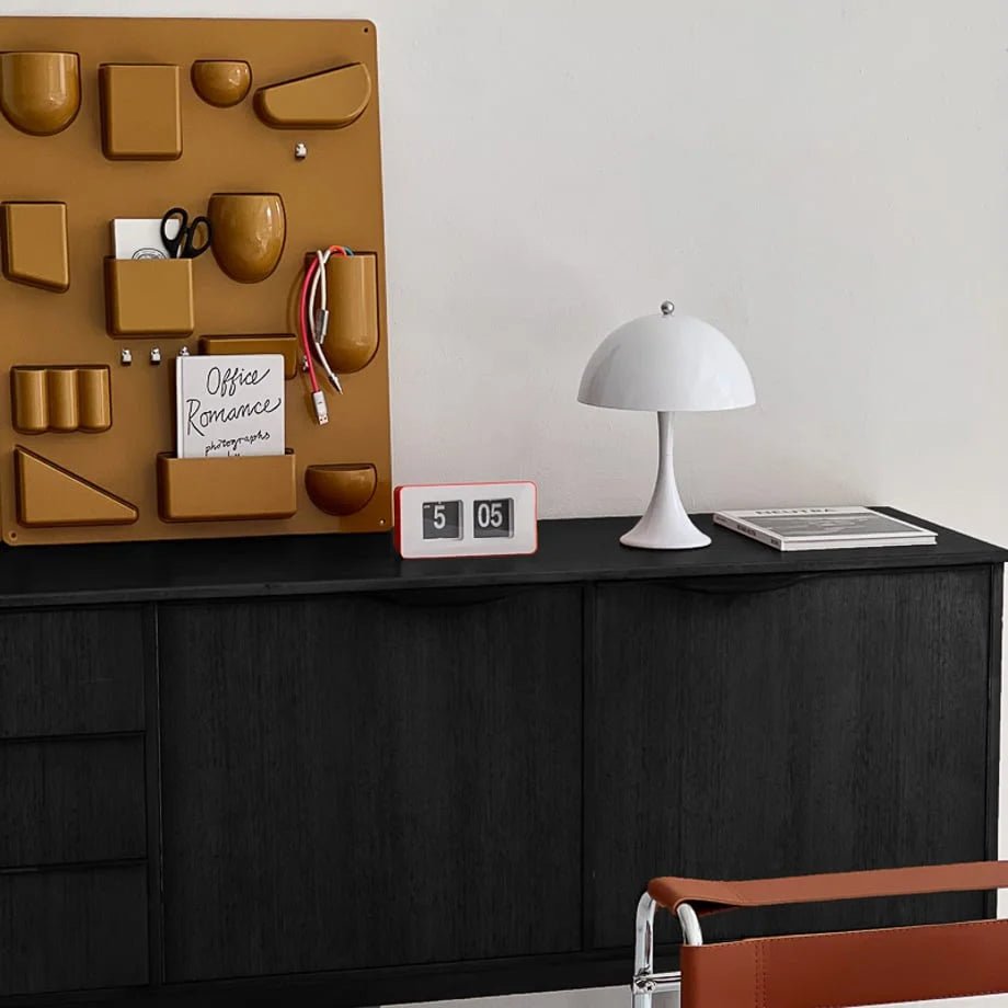 Orange retro flip clock on a black wooden desk with a white mushroom lamp and a wall organizer. - RoomDen