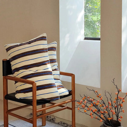 The cream and brown striped velvet pillowcases displayed on a wooden chair - RoomDen.