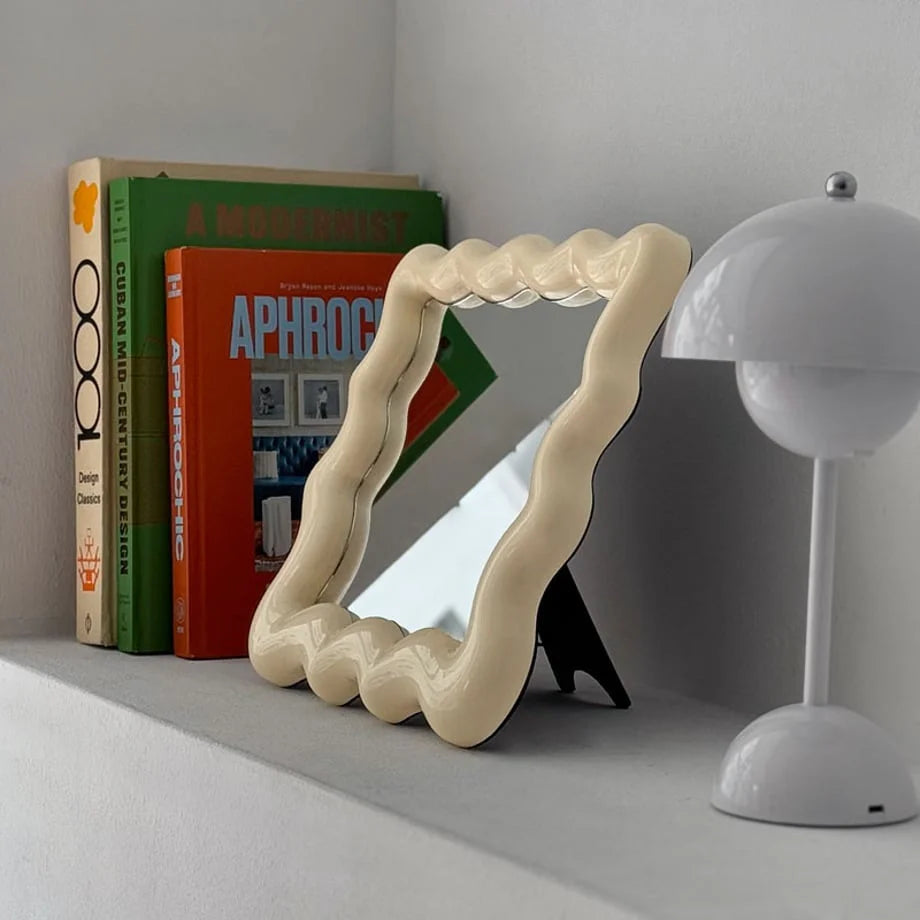 Side profile of the cream wavy mirror showing its black easel stand for tabletop display - RoomDen