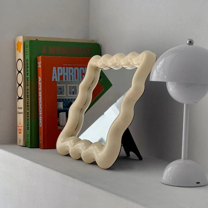 Side profile of the cream wavy mirror showing its black easel stand for tabletop display - RoomDen