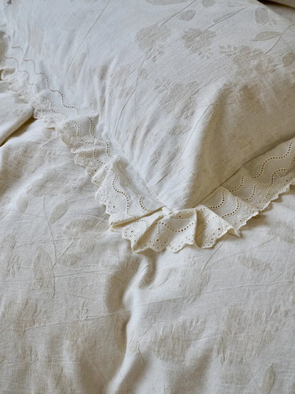 Detail shot of textured linen fabric with subtle flower pattern and lace edges RoomDen.