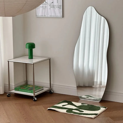 RoomDen green abstract art rug styling shot with a chrome table and green lamp.