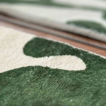 Detail shot of the dense green and white tufted pile texture of the art rug.