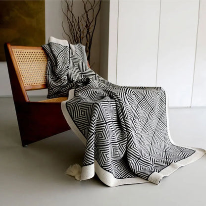 Black and white diamond knit fleece throw blanket draped over a wooden chair - RoomDen
