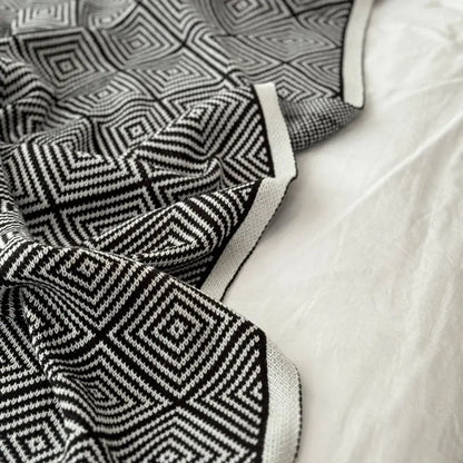 Black and white diamond knit fleece throw blanket draped over a wooden chair - RoomDen