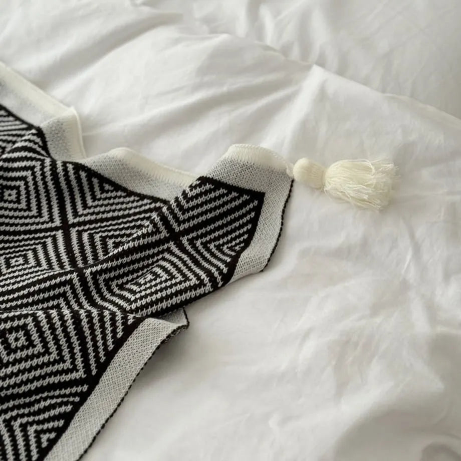 Black and white diamond knit fleece throw blanket draped over a wooden chair - RoomDen