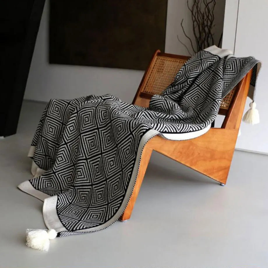 Black and white diamond knit fleece throw blanket draped over a wooden chair - RoomDen