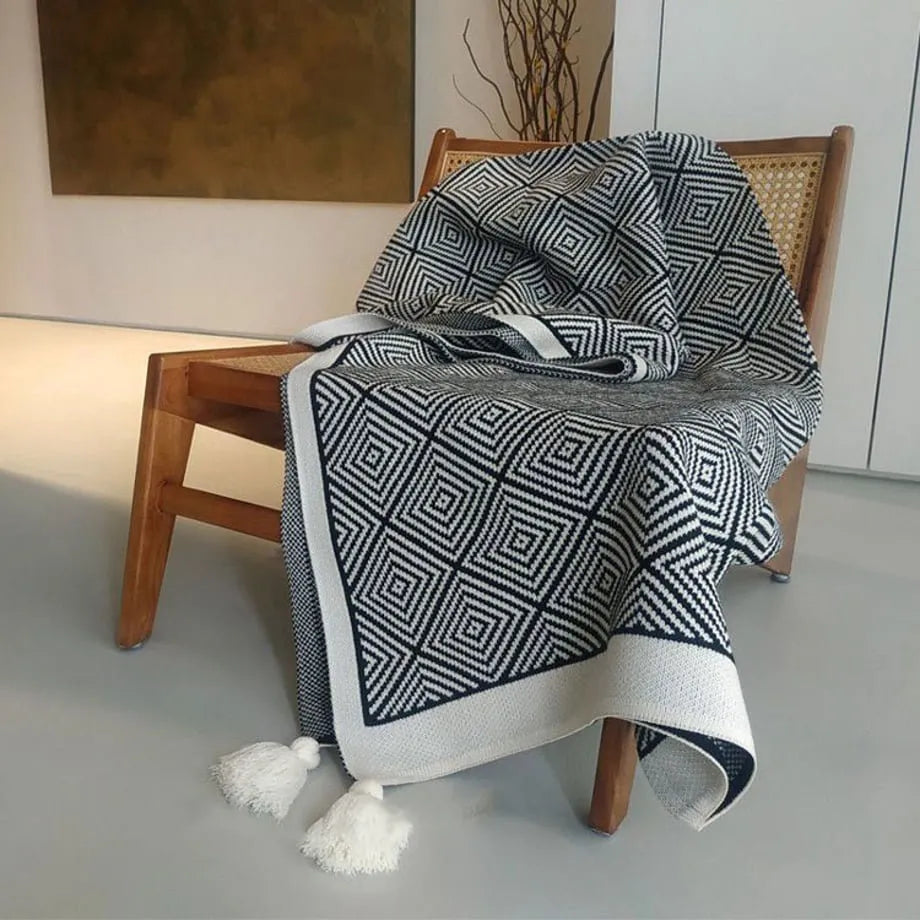 Black and white diamond knit fleece throw blanket draped over a wooden chair - RoomDen