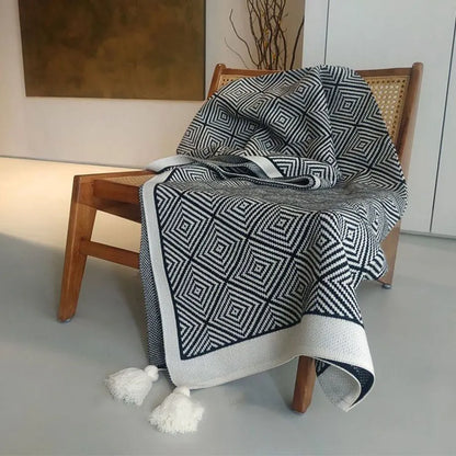 Black and white diamond knit fleece throw blanket draped over a wooden chair - RoomDen