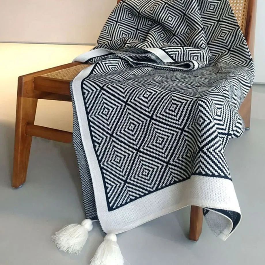 Black and white diamond knit fleece throw blanket draped over a wooden chair - RoomDen