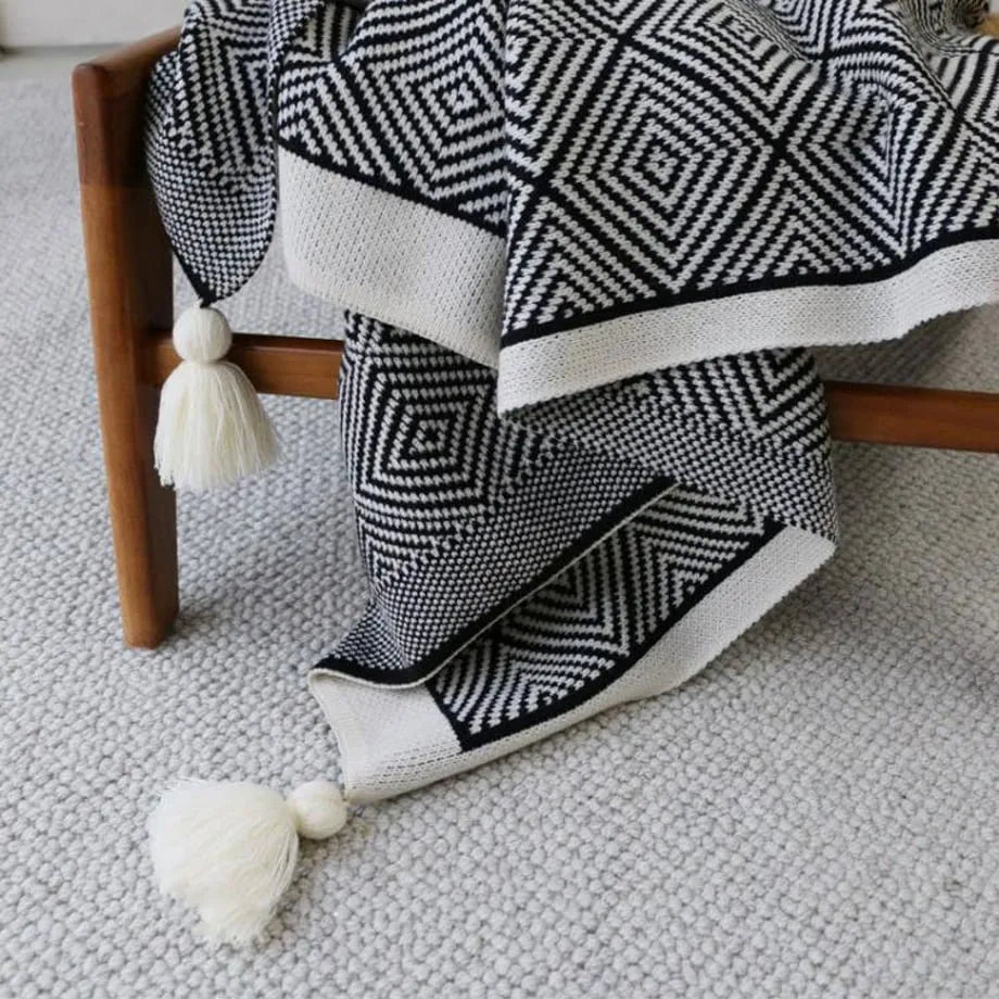 Black and white diamond knit fleece throw blanket draped over a wooden chair - RoomDen