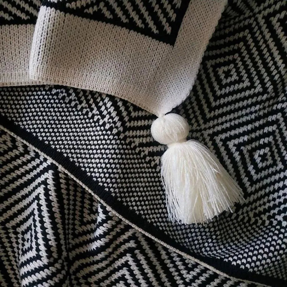 Black and white diamond knit fleece throw blanket draped over a wooden chair - RoomDen