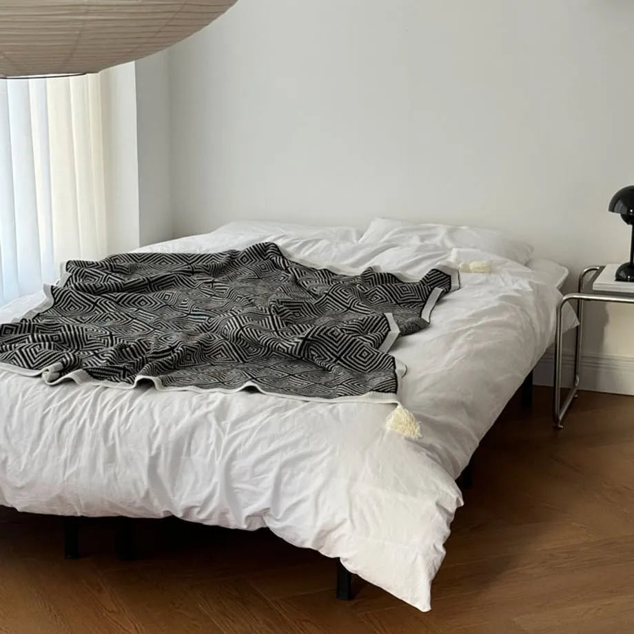 Black and white diamond knit fleece throw blanket draped over a wooden chair - RoomDen