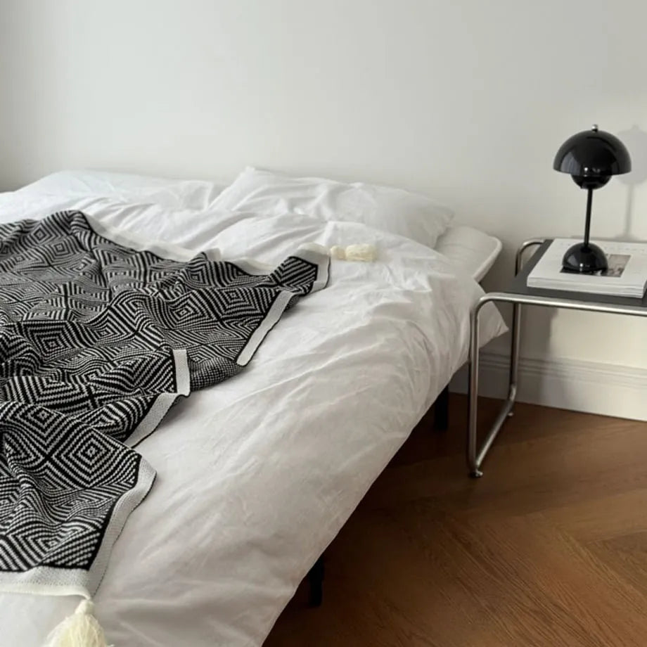 Black and white diamond knit fleece throw blanket draped over a wooden chair - RoomDen