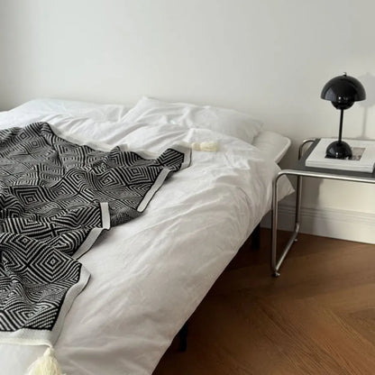 Black and white diamond knit fleece throw blanket draped over a wooden chair - RoomDen
