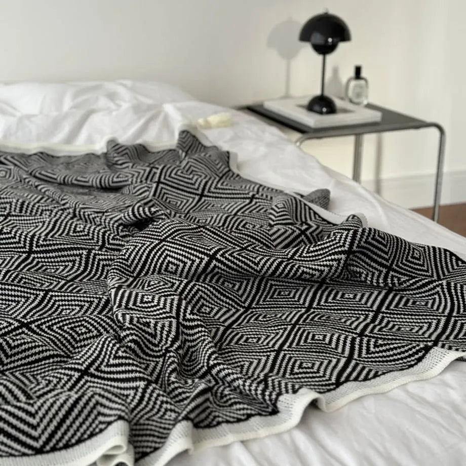 Black and white diamond knit fleece throw blanket draped over a wooden chair - RoomDen