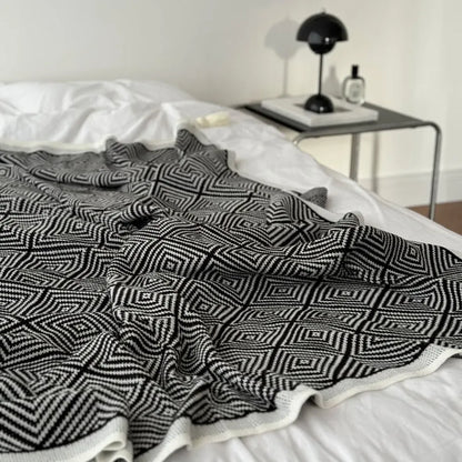 Black and white diamond knit fleece throw blanket draped over a wooden chair - RoomDen