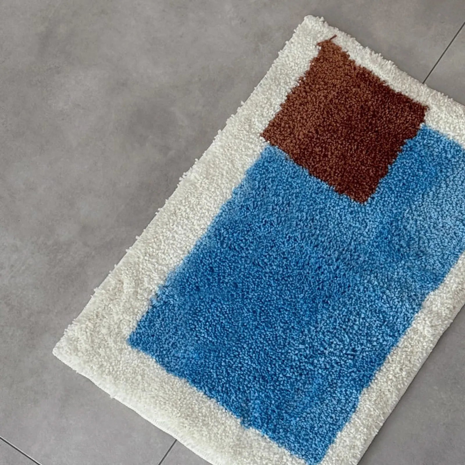 Top-down view of Modern Color Block Plush Accent Rug featuring blue and brown geometric shapes on a cream background - RoomDen