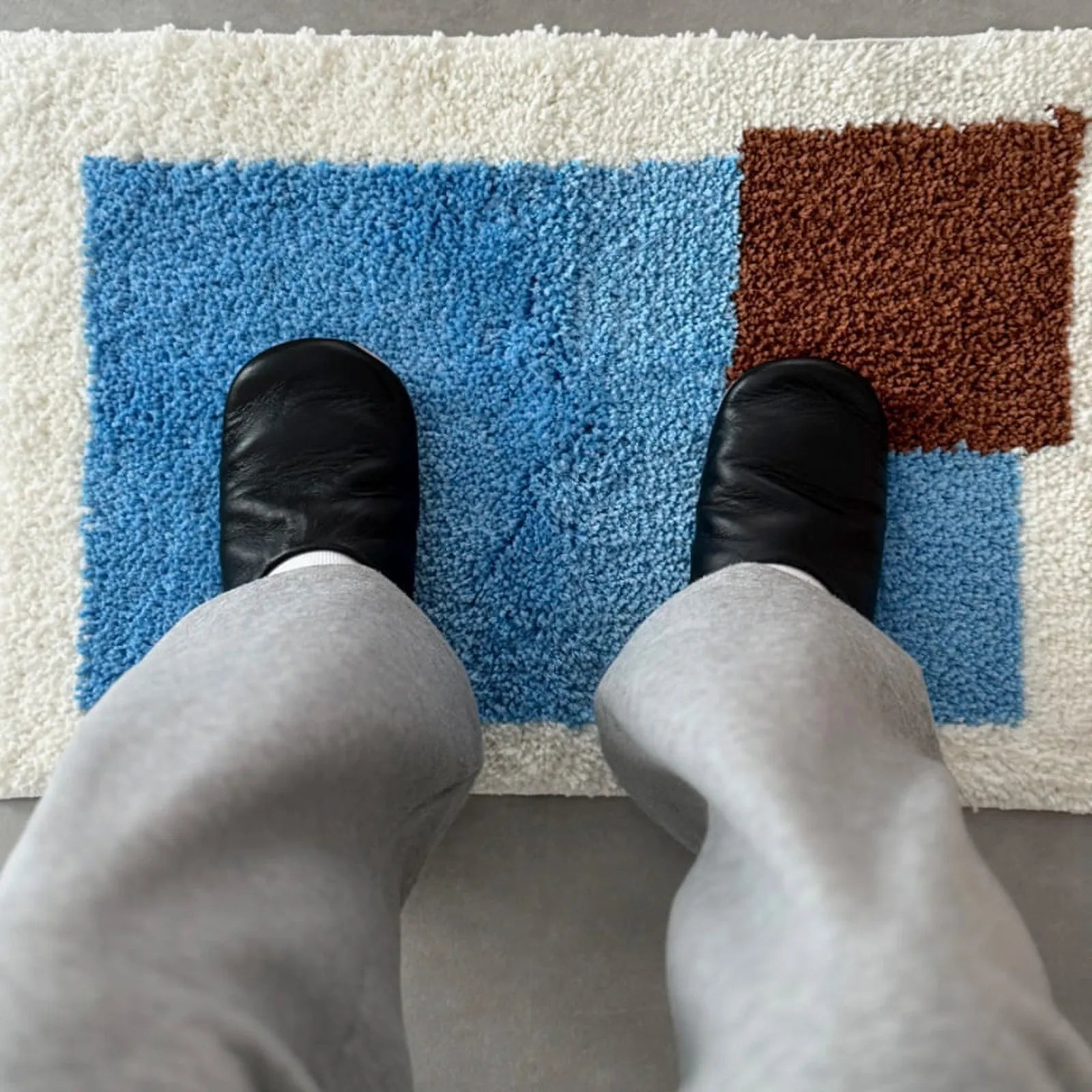 Feet standing on blue and brown color block rug