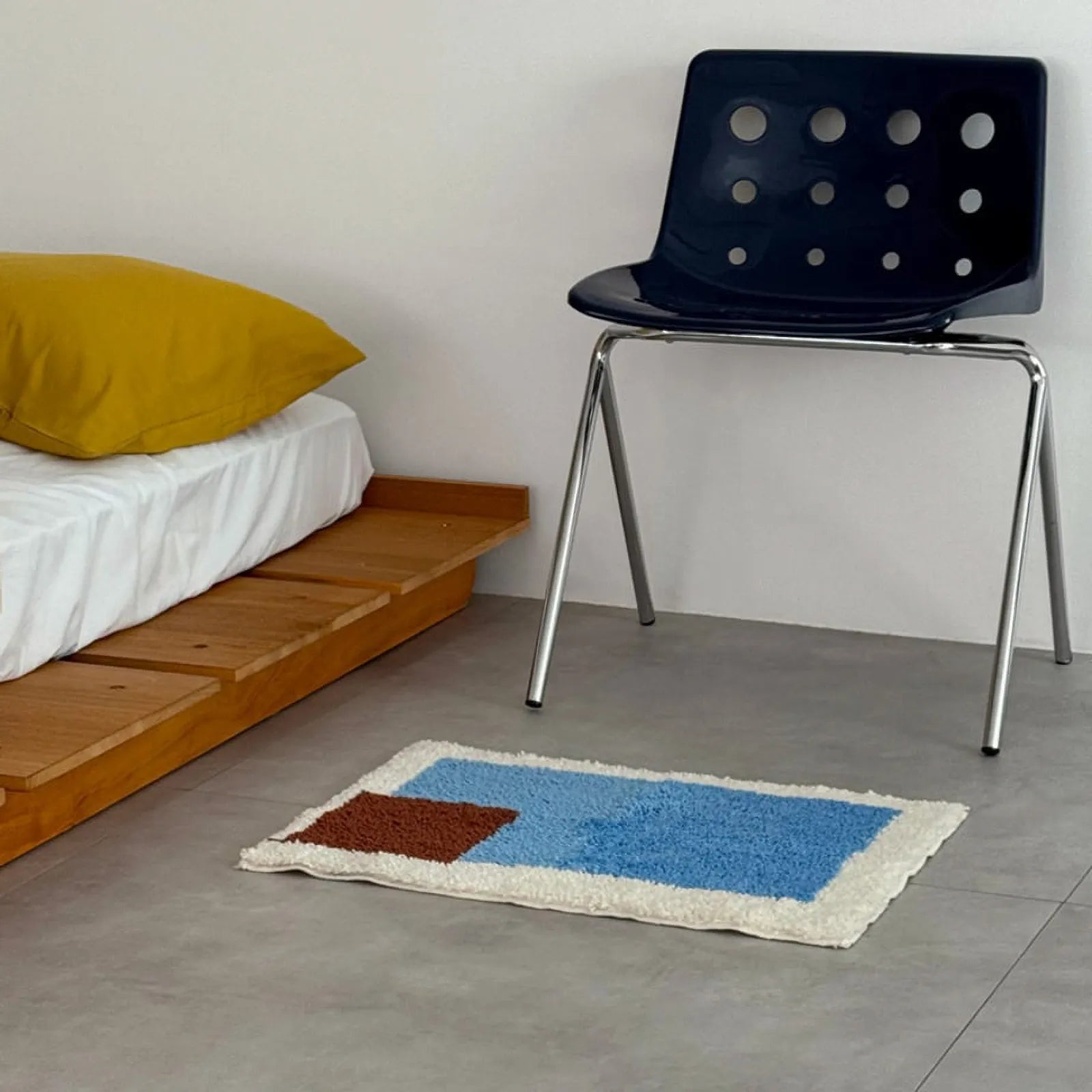 Modern Color Block Plush Accent Rug placed on the floor next to a low wooden bed and a blue chair - RoomDen