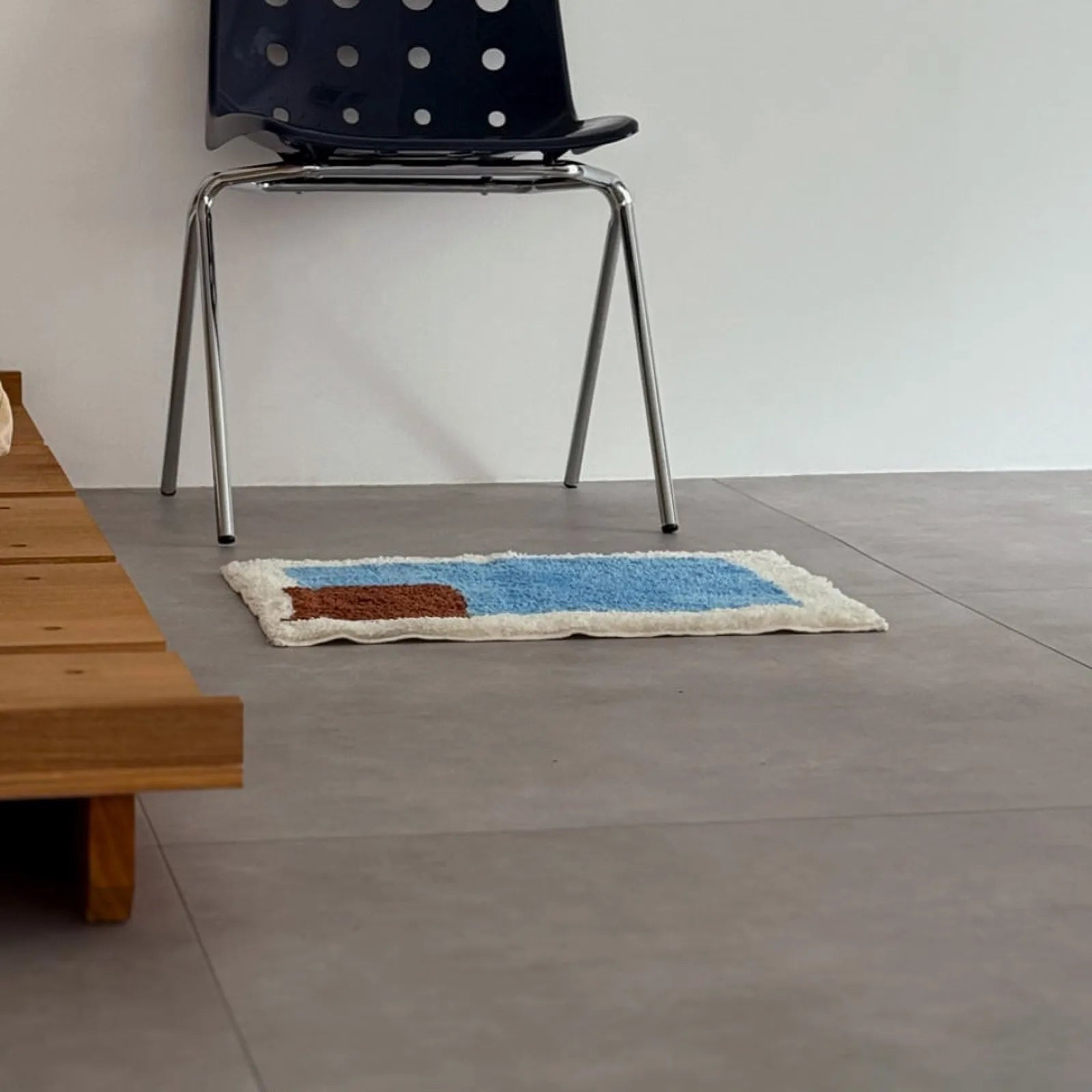 Eye-level view of Modern Color Block Plush Accent Rug on grey tiled floor near bed frame and chair legs - RoomDen