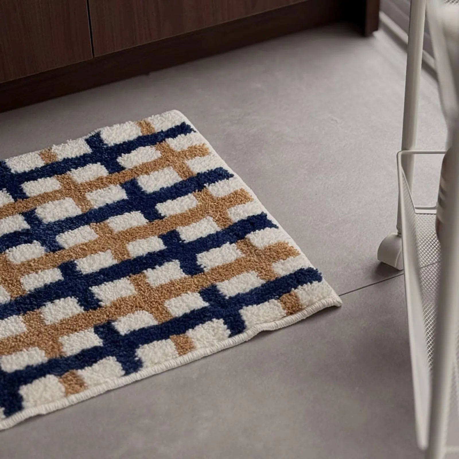 Angled view of navy and tan grid shaggy rug on grey floor near white cart - RoomDen