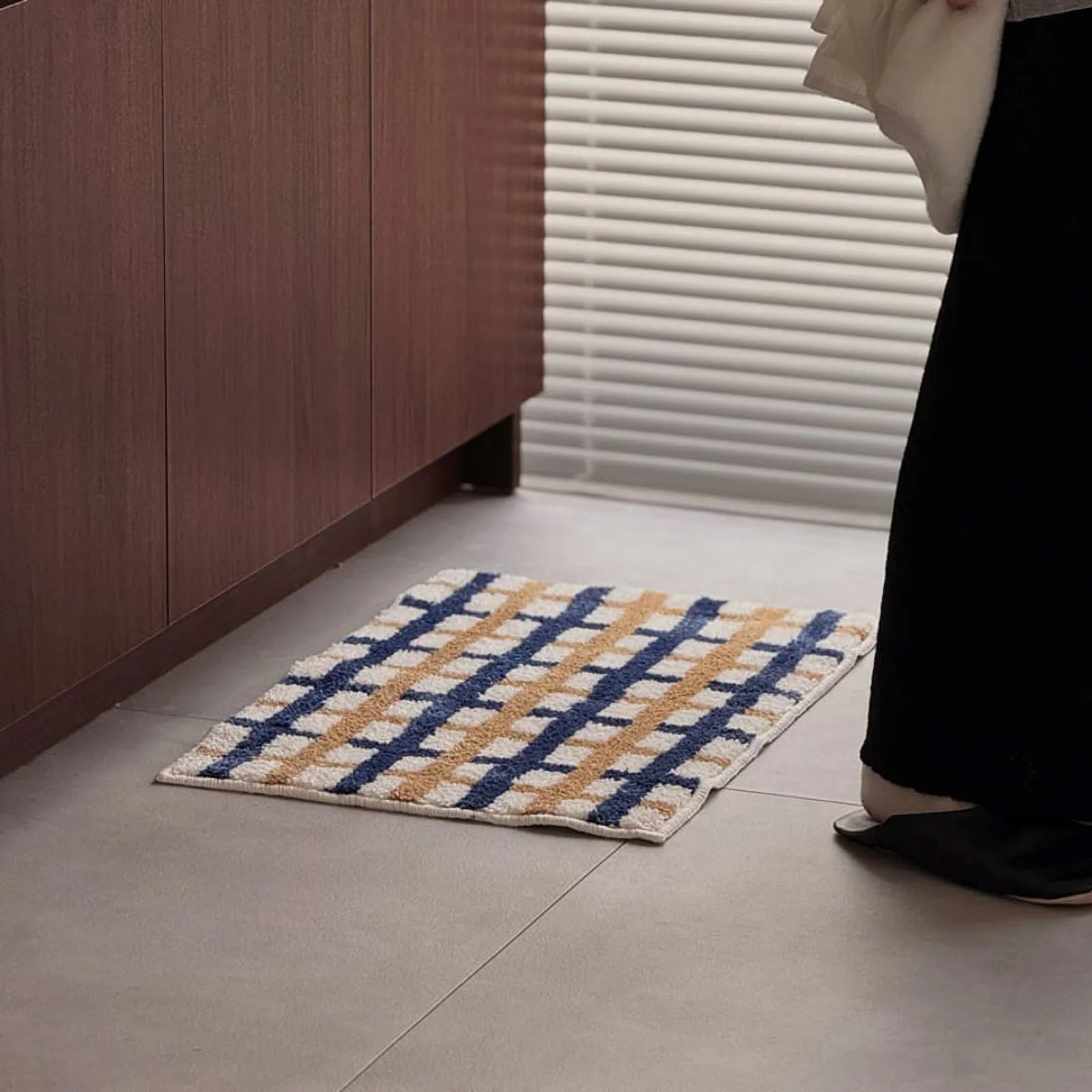 Lifestyle shot of person standing next to the checkered rug near a window - RoomDen