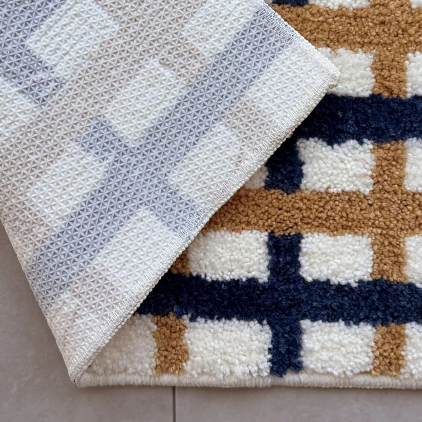 Detail view of the white geometric TPR non-slip backing folded over - RoomDen
