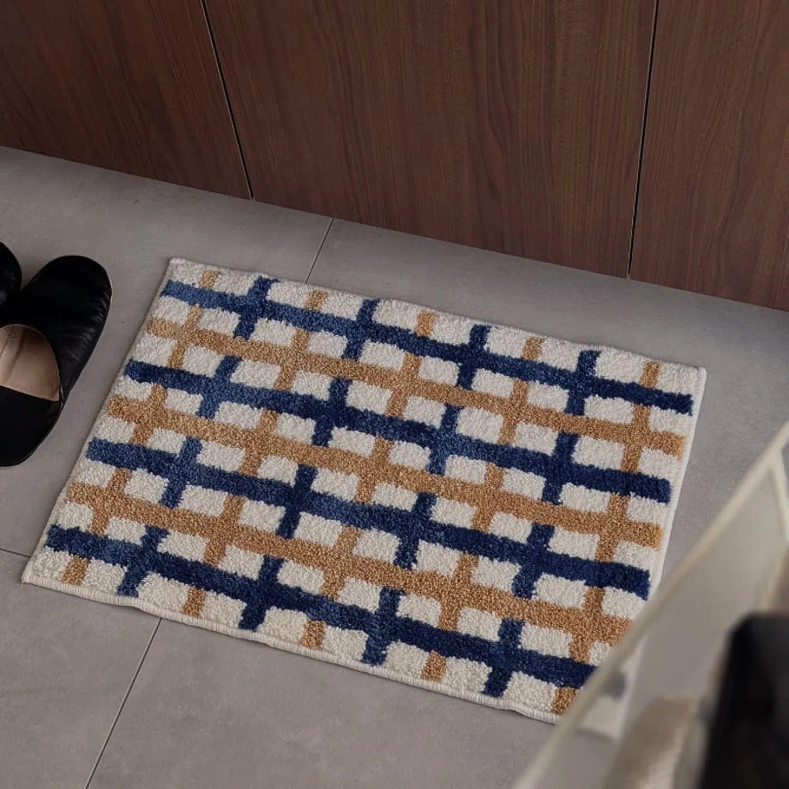 Top-down view of the grid pattern rug placed near black slippers - RoomDen