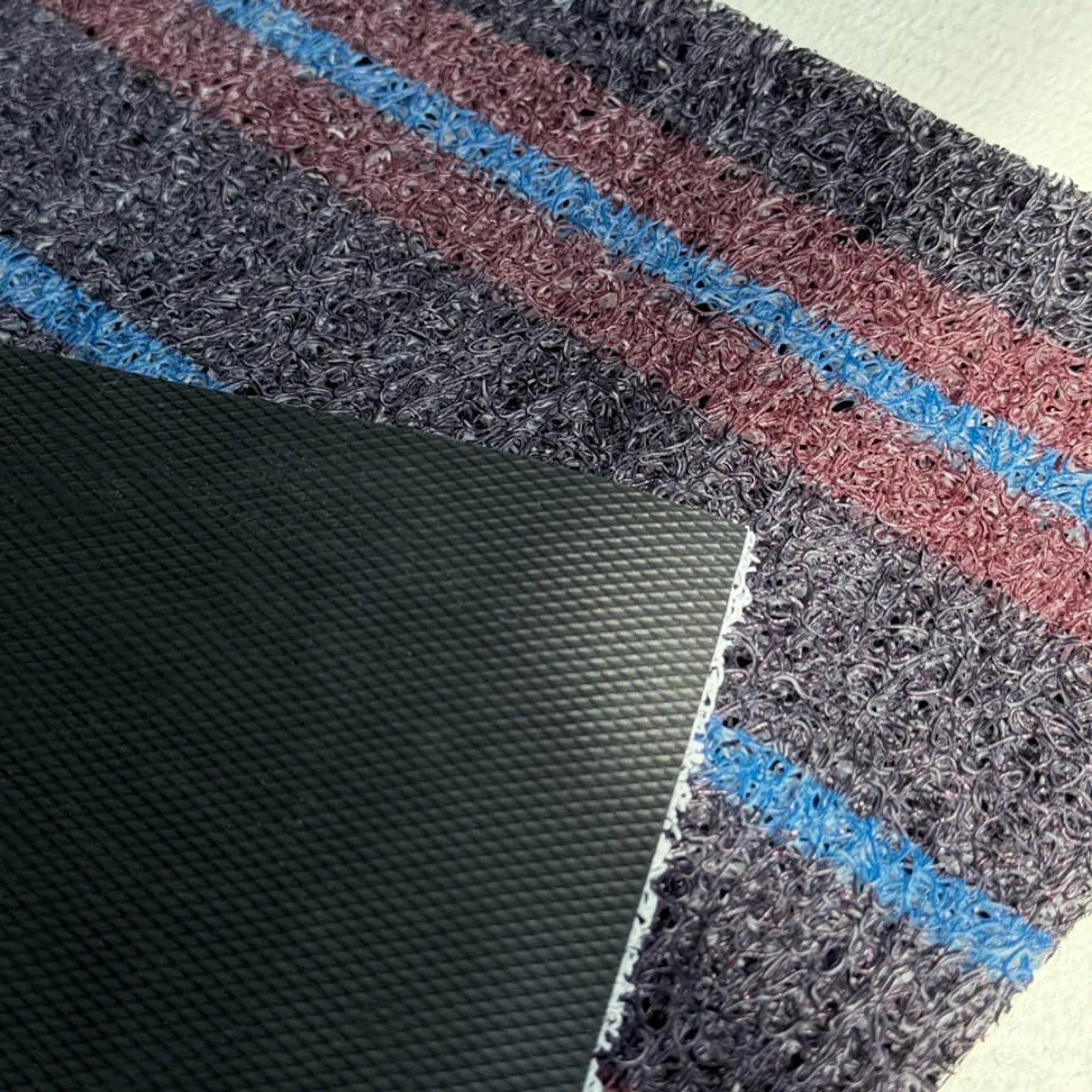 Macro shot showing the thickness and dual-layer structure of the dark grey coil mat.