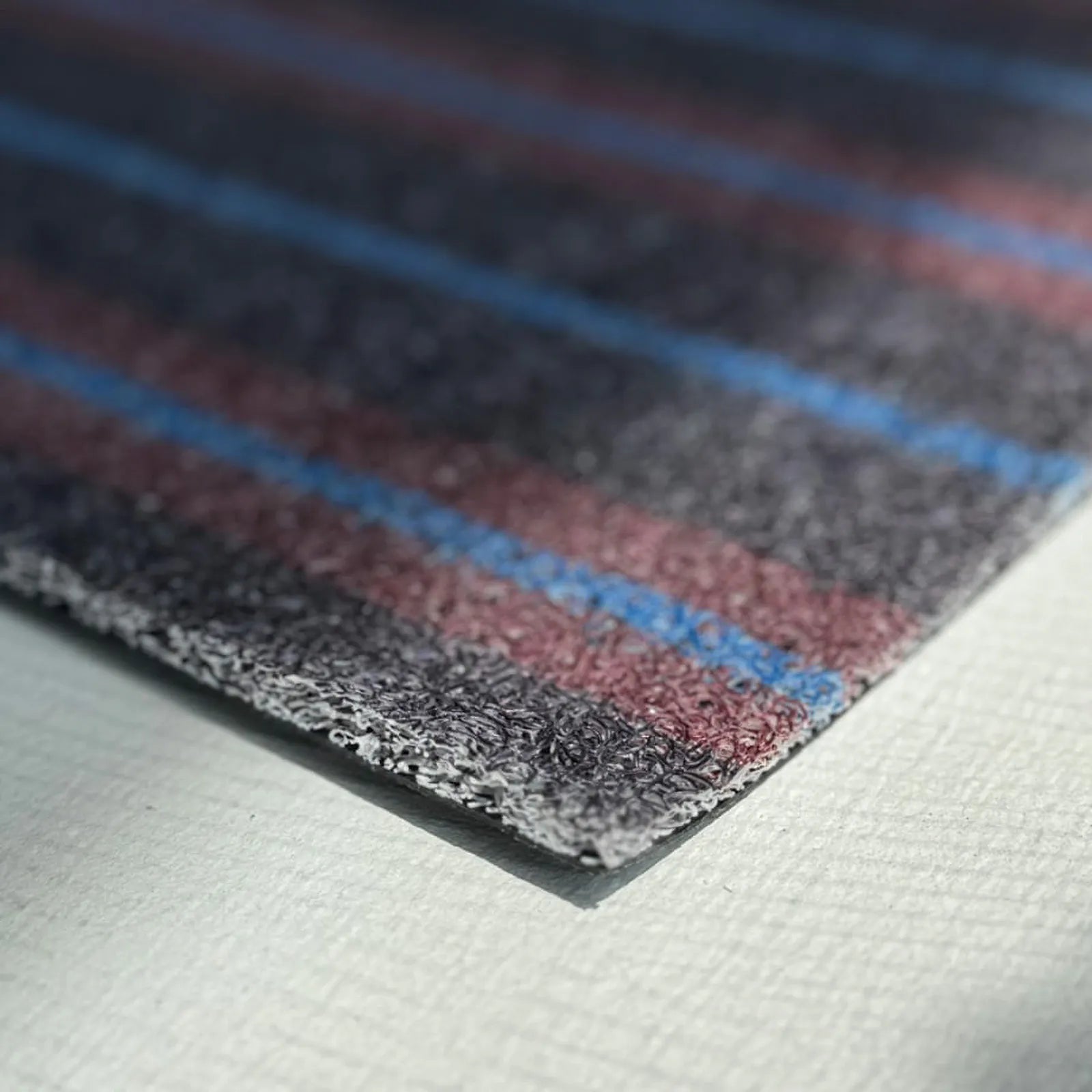 Extreme close-up of the mat edge revealing the grey loops and black non-slip backing layer.