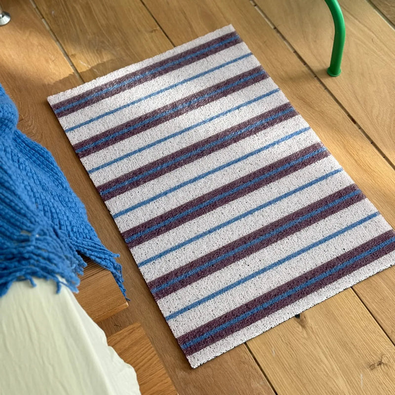 High-angle view of a white pinstripe coil rug placed on wooden flooring - RoomDen