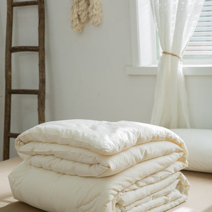 Layered plant-based down alternative insert folded on beige sheet - RoomDen