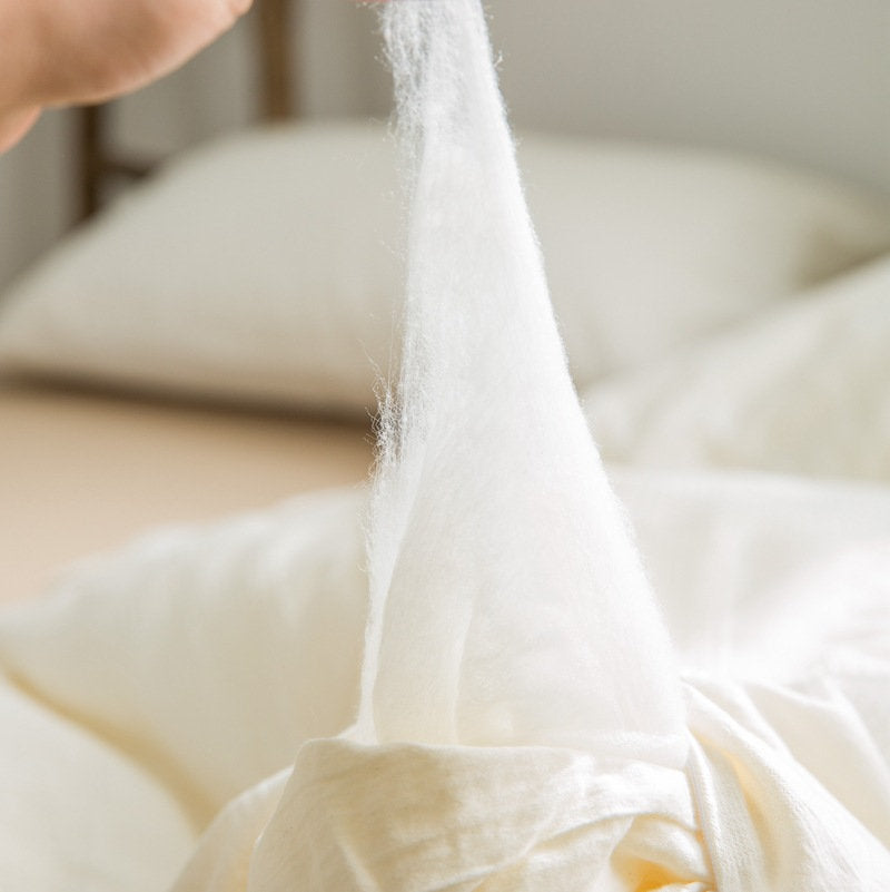 Soft soy-fiber filling of eco down alternative duvet insert being stretched by hand - RoomDen