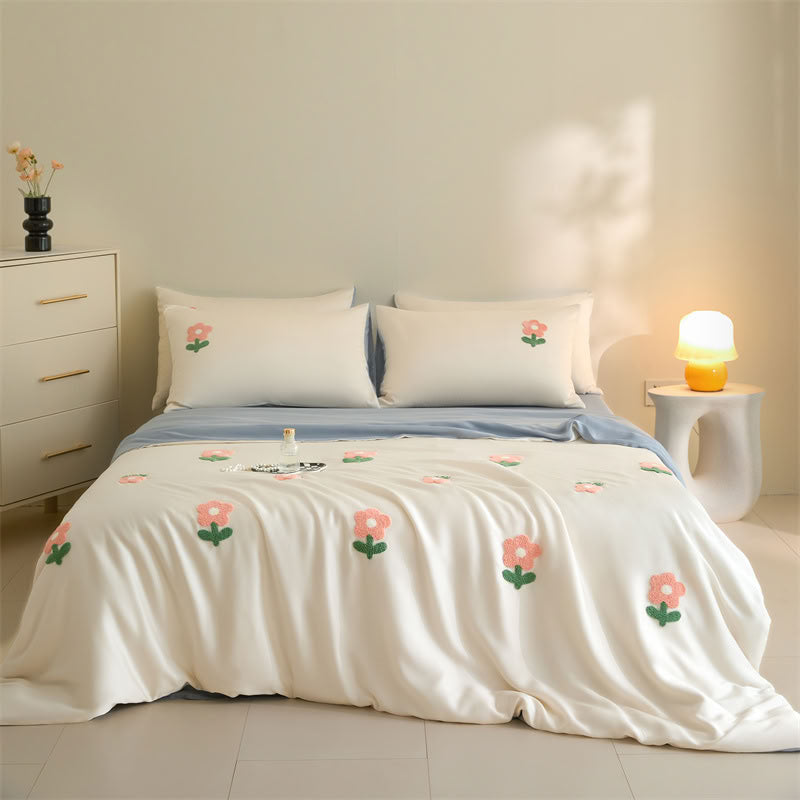 Minimalist bedroom with blue bedsheet and white duvet featuring embroidered flowers - RoomDen