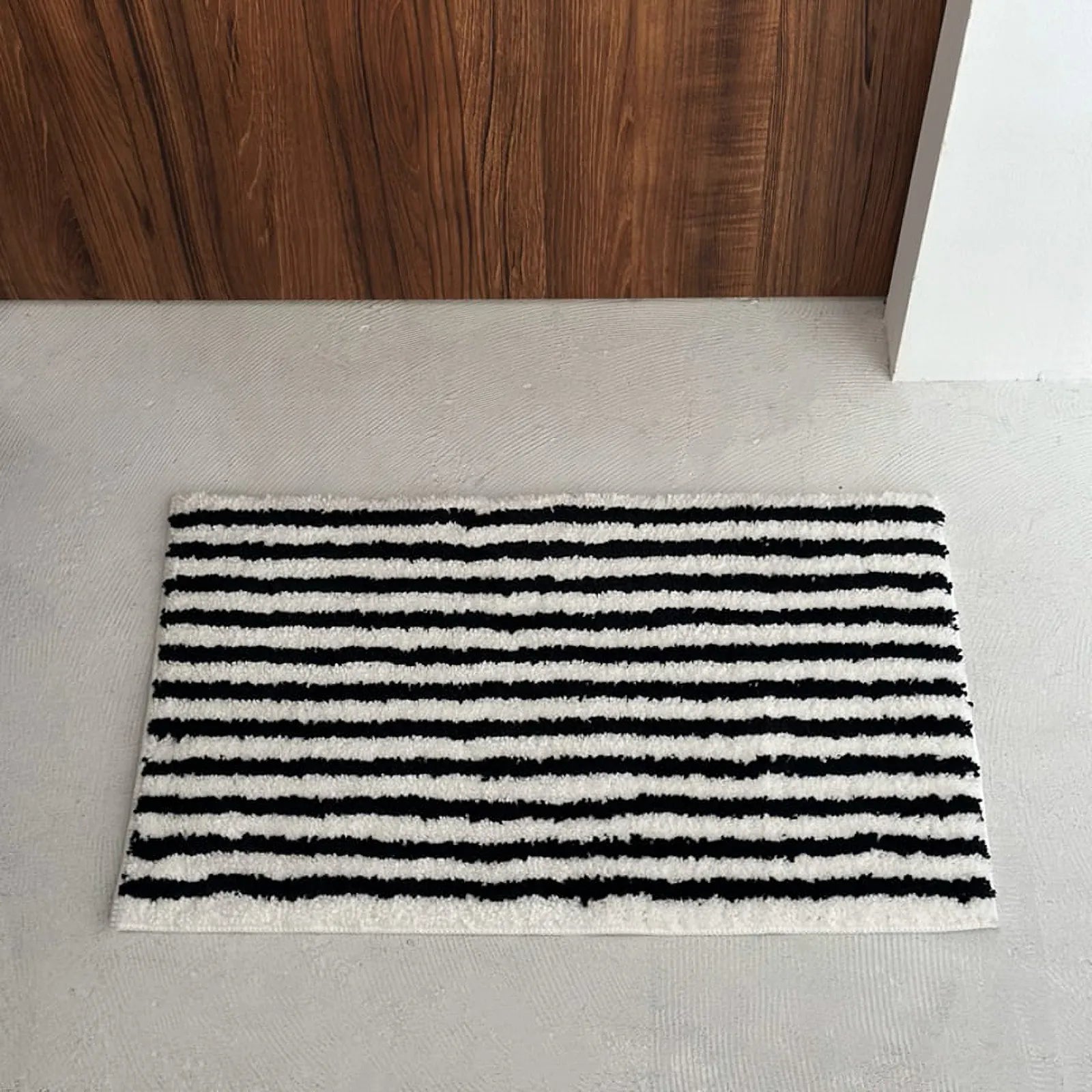 Top down view of black and white shaggy rug on grey floor - RoomDen