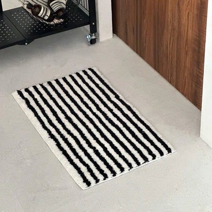 Angled view of black wavy stripe rug next to wooden wall panel - RoomDen