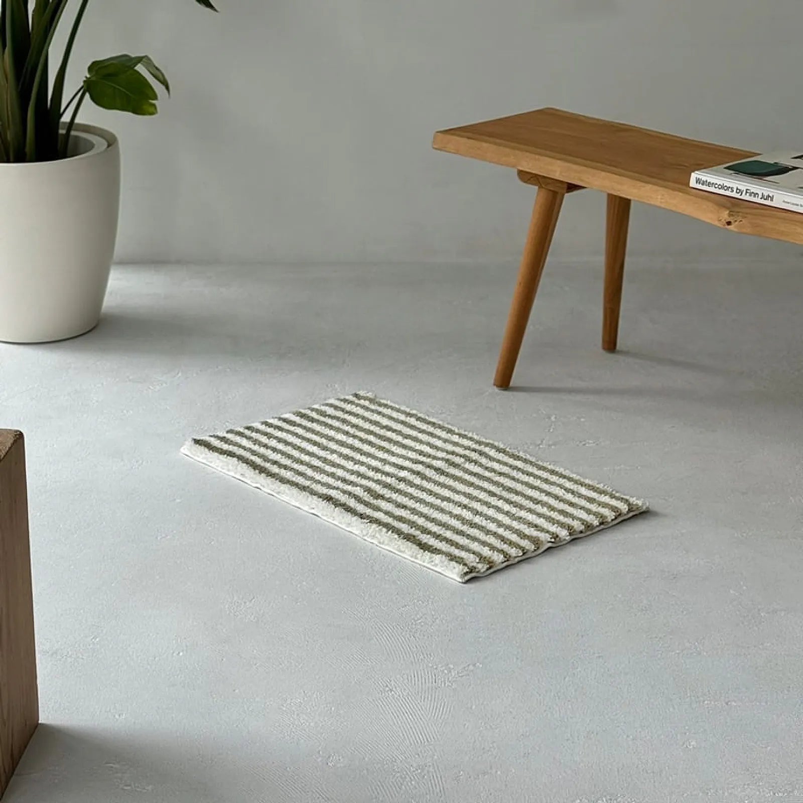 Olive green and cream wavy striped rug on grey concrete floor - RoomDen